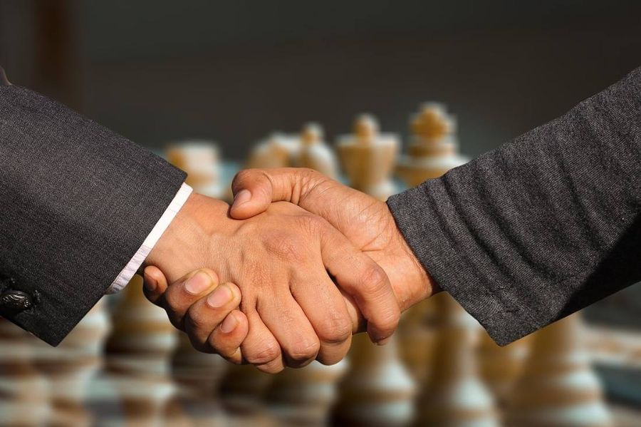Two business partners shaking hands over a negotiation table